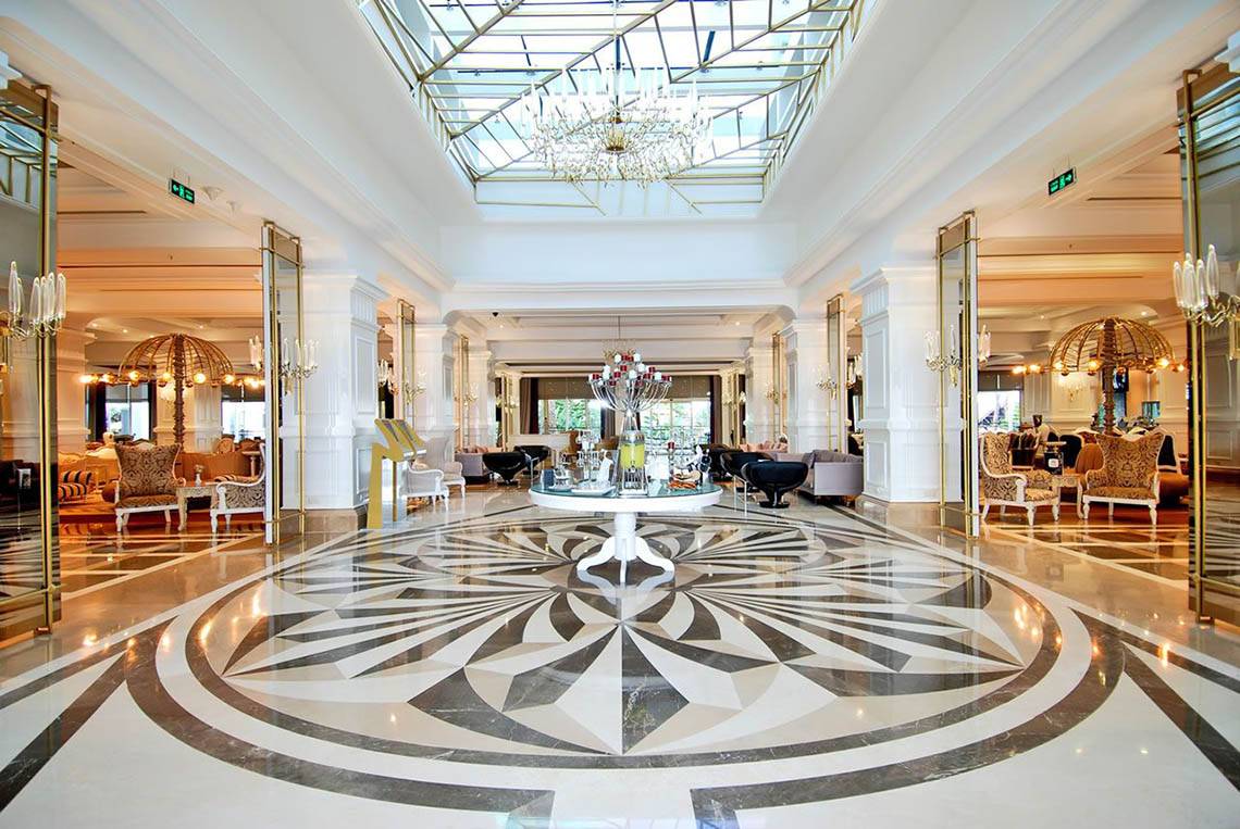 Empfangsbereich des Delphin Diva Premiere Hotels mit zentralem Tisch und Kronleuchter.