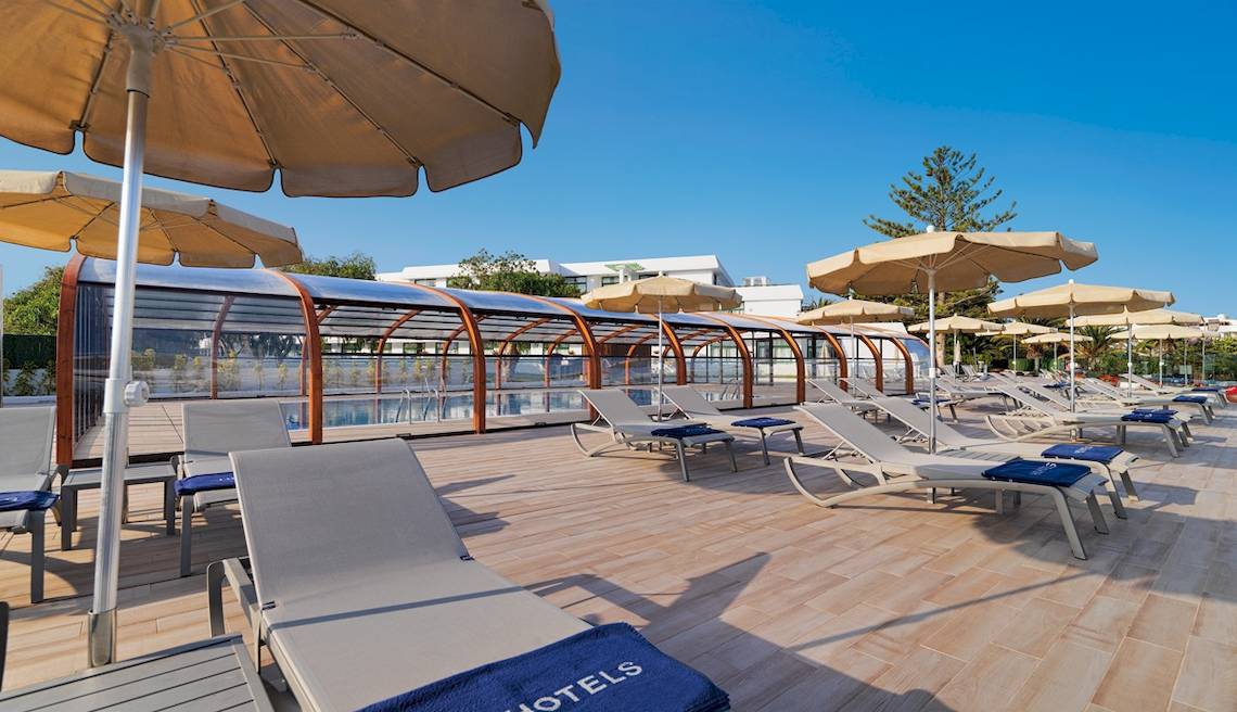 Pool-Loungebereich des H10 Lanzarote Princess Hotels mit Sonnenliegen und Sonnenschirmen.