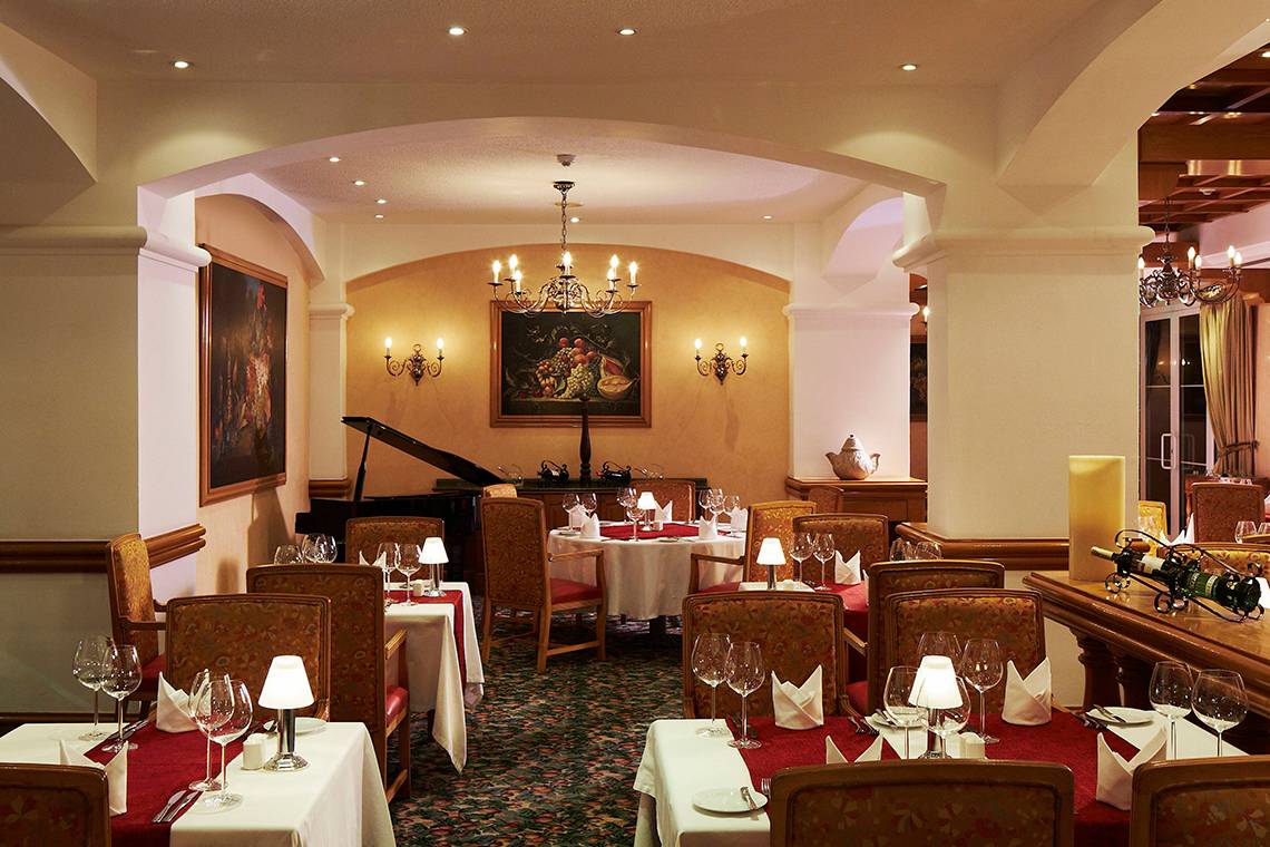 Innenansicht des Restaurants im Hurghada Marriott Beach Resort mit eingerichteten Tischen, Stühlen und einer Klavierecke.