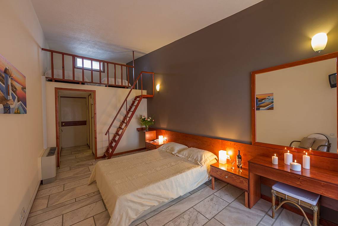 Ein Schlafzimmer im Pavlina Beach Hotel mit zwei Betten, einer Treppe und einem Balkon.