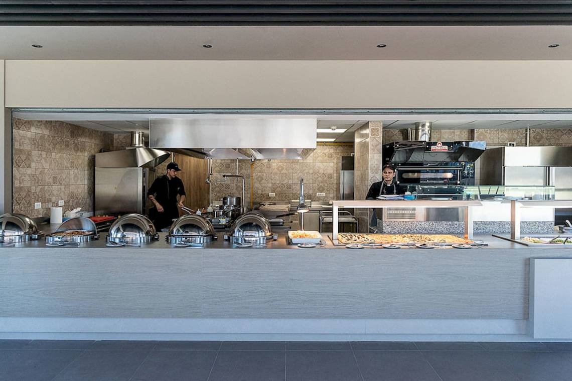 Innenansicht der Küche im Euphoria Resort mit zwei Mitarbeitern, die hinter einem Buffet mit Speisen stehen.