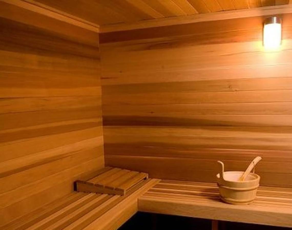 Innenansicht einer Sauna im Queens Bay Hotel mit Holzwänden und Sitzbänken.
