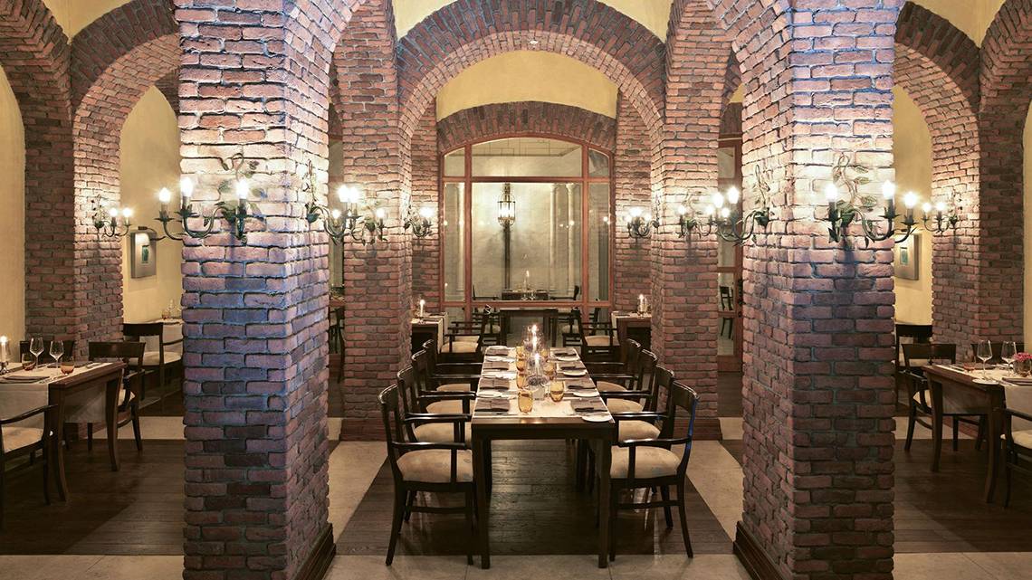 Innenansicht des Restaurants im Kempinski Hotel The Dome Belek mit roten Ziegelwänden und runden Säulen.