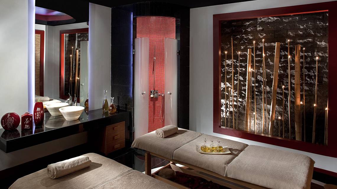 Spa-Behandlungsraum im Kempinski Hotel The Dome Belek mit zwei Massageliegen, Waschbecken und Wanddekoration.