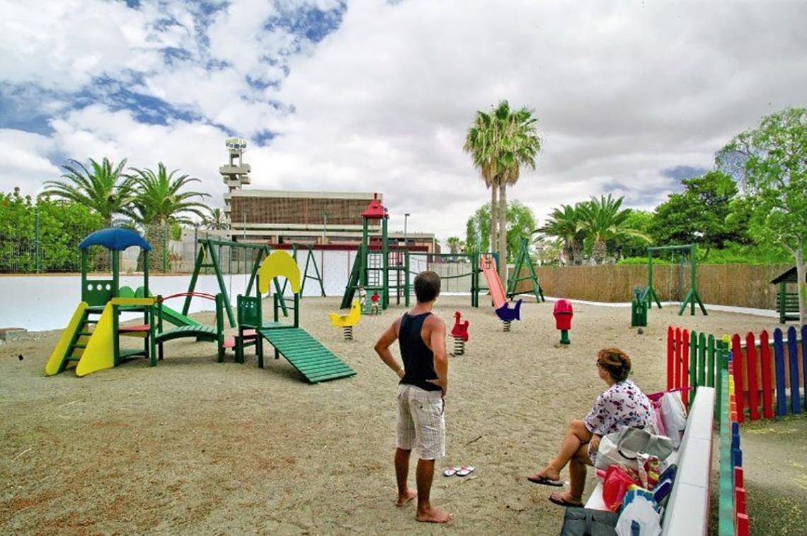 Spielplatz im Alborada Ocean Club Hotel mit bunten Spielgeräten und einem Erwachsenen, der darauf blickt.