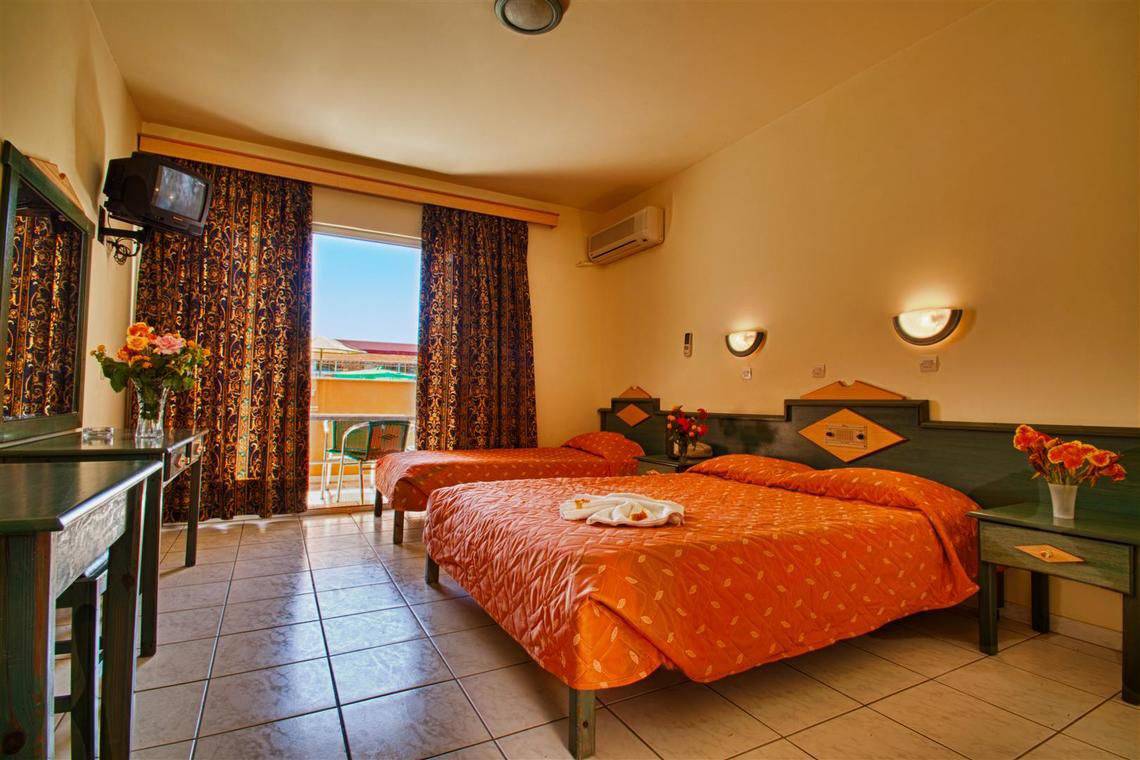 Hotelzimmer im Ilios K. Village Resort mit zwei Betten, Fernseher und Balkon.