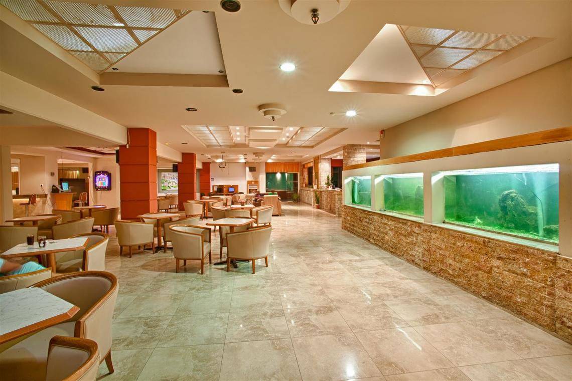 Loungebereich des Ilios K. Village Resorts mit Tischen, Stühlen und großen Aquarien.