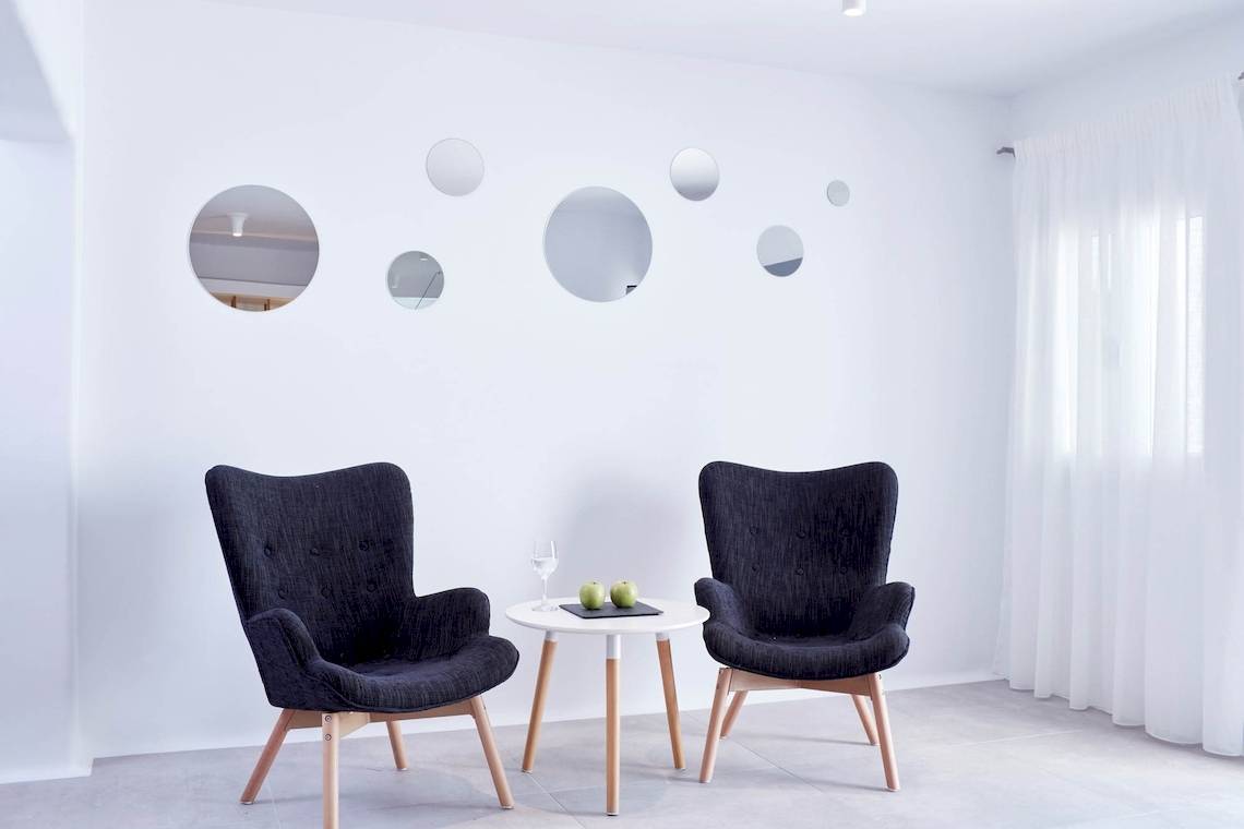 Lobby Sitzecke im Absolute Mykonos Suites & More Hotel mit weißen Wänden und runden Spiegeln.