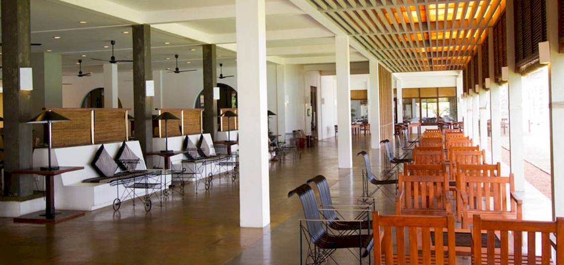 Innenbereich des Blue Water Hotel und Spa mit langen Tischen und Stühlen, Holzmöbeln und Deckenventilatoren.