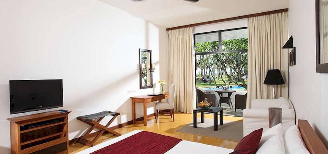 Hotelzimmer mit modernem Interieur, Fernseher, Schreibtisch und Blick auf einen Swimmingpool.