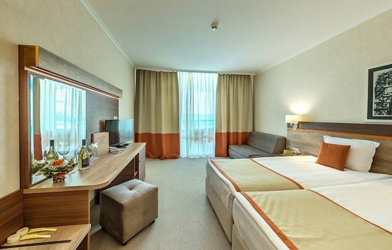 Doppelzimmer im Festa Panorama Hotel mit zwei Betten, Schreibtisch, Spiegel, Sofa und Fenstern.