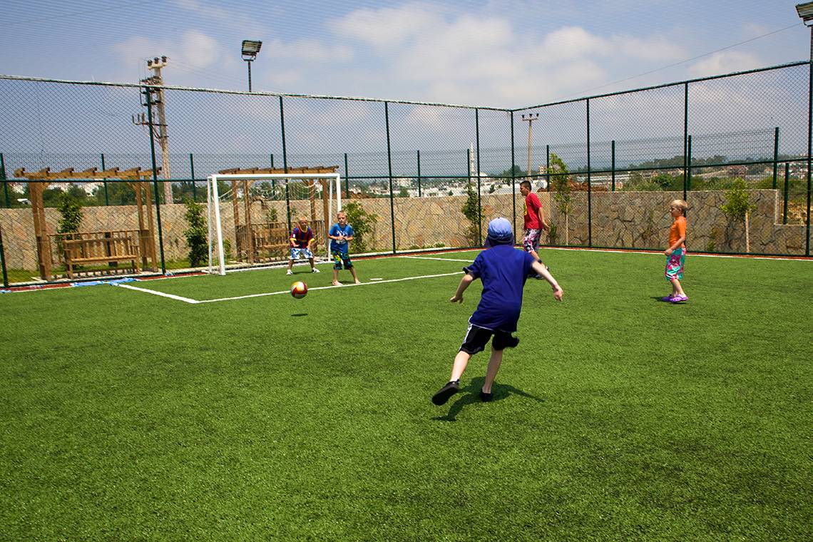 Kinder stoßen Fußball auf Rasen im Eftalia Aqua Resort Hotel