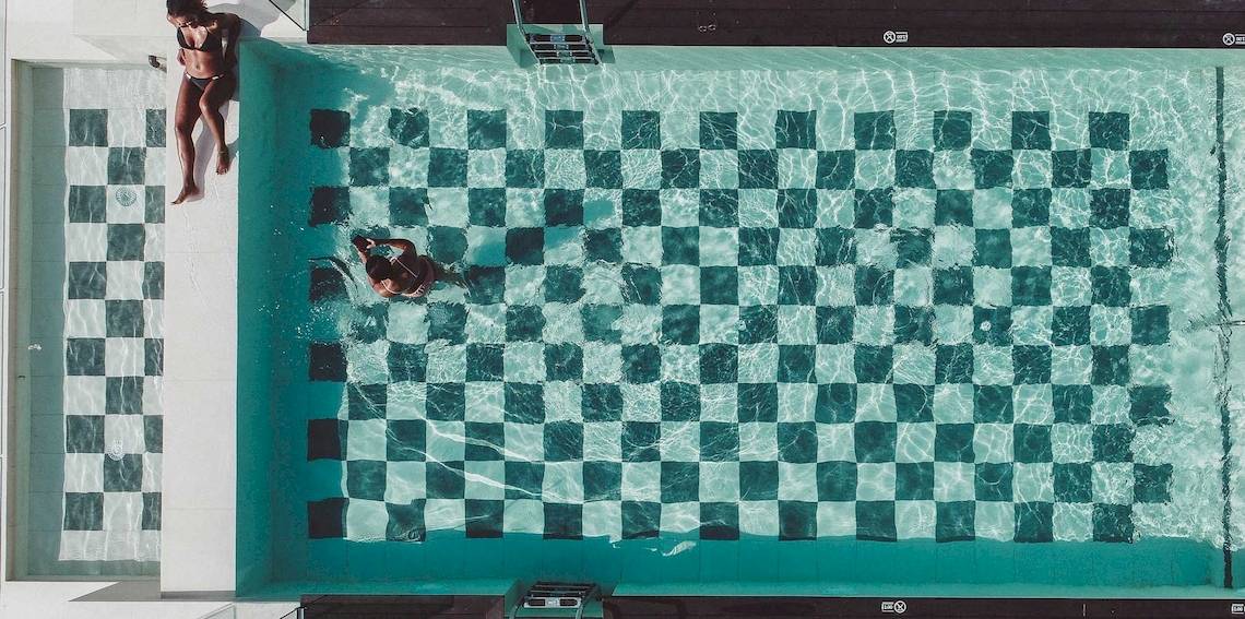 Oberflaechenansicht des Schwimmbeckens im Amare Beach Hotel Ibiza mit zwei Personen, die im Wasser schwimmen.