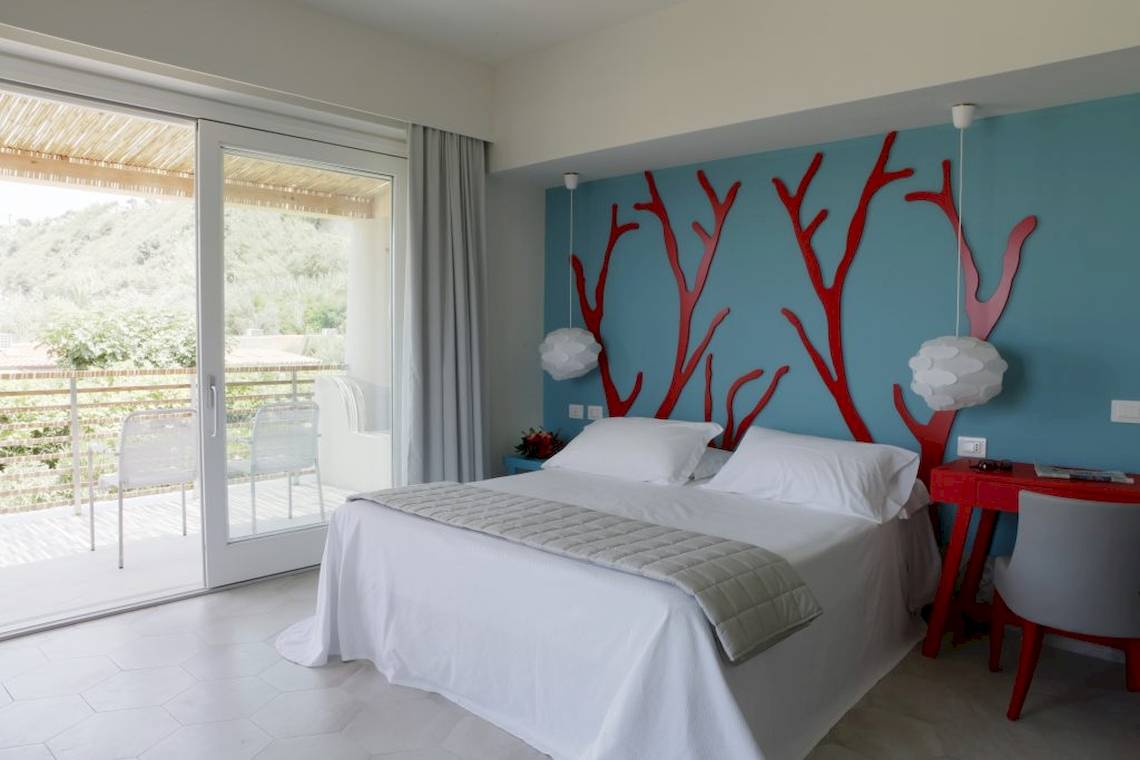 Hotelzimmer im Baia del Sole mit einem Bett, rotem Wanddesign und einem Balkon