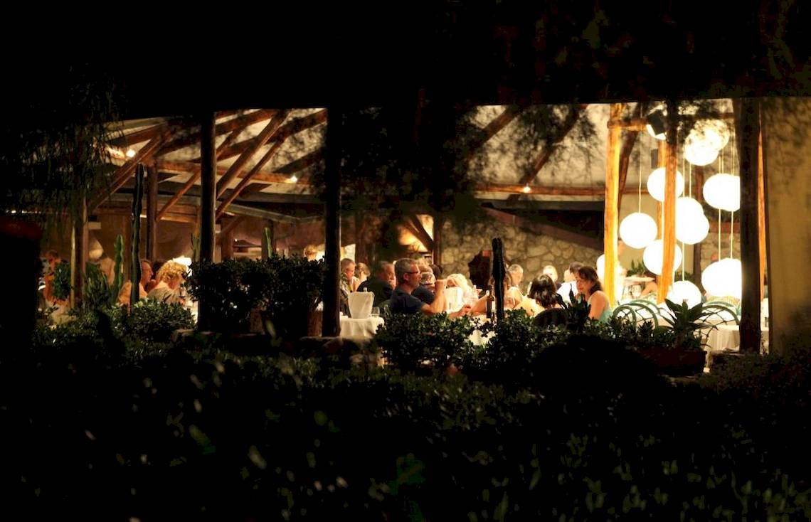 Ein Hotelgäste feiern bei einem Abendessen unter einem Sternenhimmel im Freien.