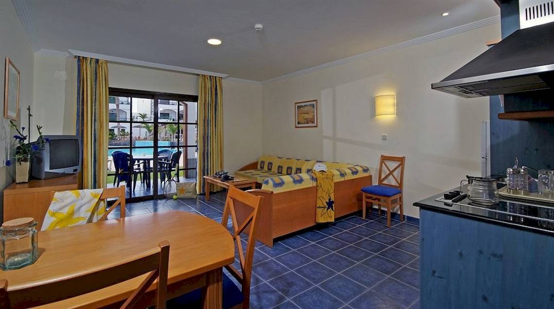Einrichtung eines Zimmers im Mirador Papagayo by LIVVO Hotel mit Wohnzimmer, Esstisch und Küche.