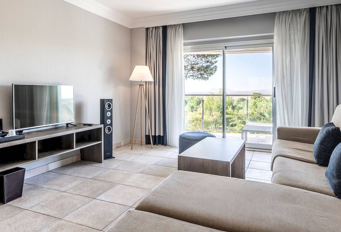 Wohnzimmer mit Fernseher, Lautsprechern, Couch und Fenstern im Sarena de Muro Resort Mallorca