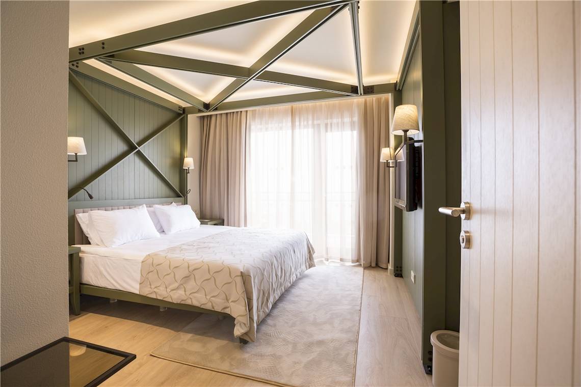 Schlafzimmer im Voyage Sorgun Hotel mit grünen Wänden, einem Bett und Fenstern.