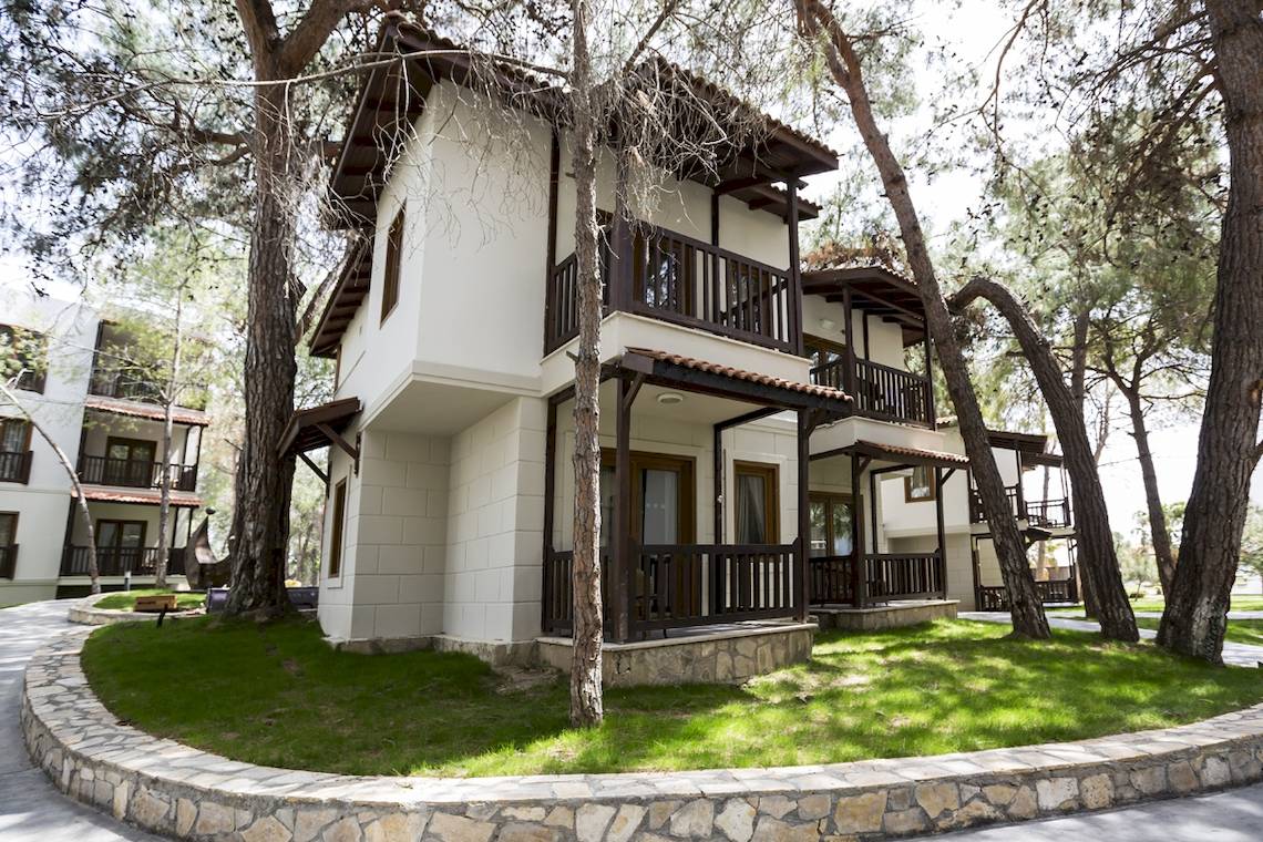 Außenansicht des Voyage Sorgun Hotels mit grünem Rasen und Bäumen.