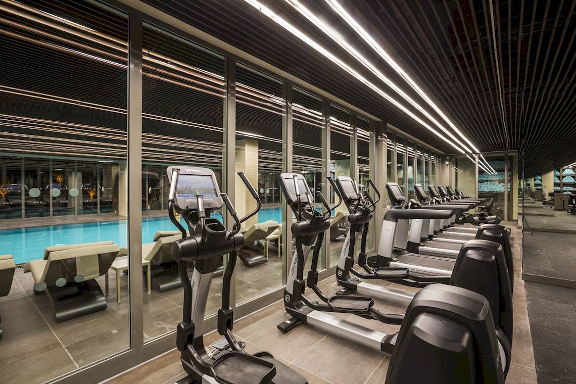 Fitnessstudio im Voyage Sorgun Hotel mit Laufbändern und Blick auf den Pool.