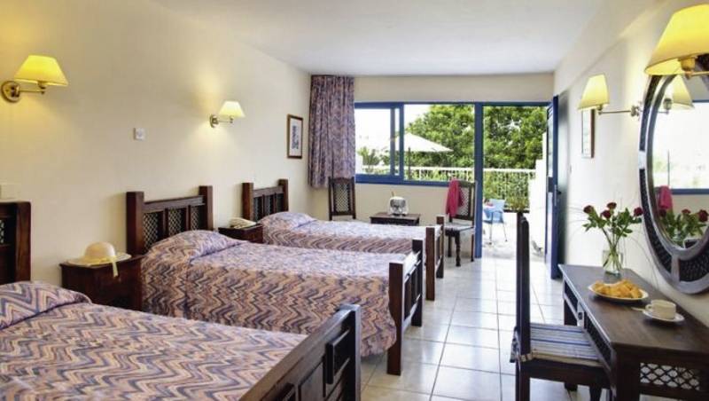 Ein Zimmer im Bella Napa Bay Hotel mit vier Betten, einem Tisch, einem Spiegel und einer Terrasse.