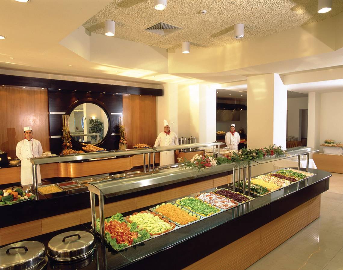 Buffettisch im Hotel Calypso Beach mit verschiedenen Gerichten und Köchen im Hintergrund.
