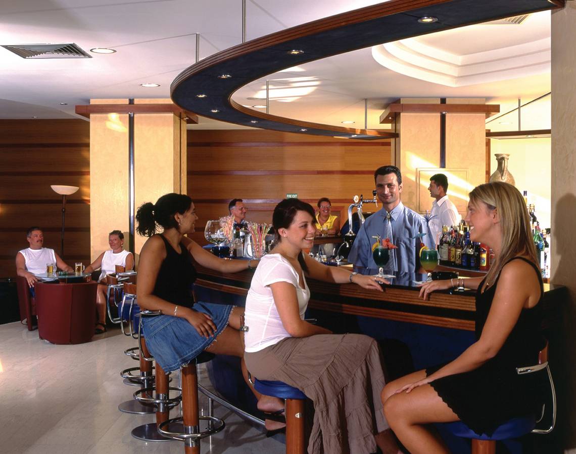 Gäste sitzen an der Bar des Calypso Beach Hotels und unterhalten sich mit dem Barkeeper.