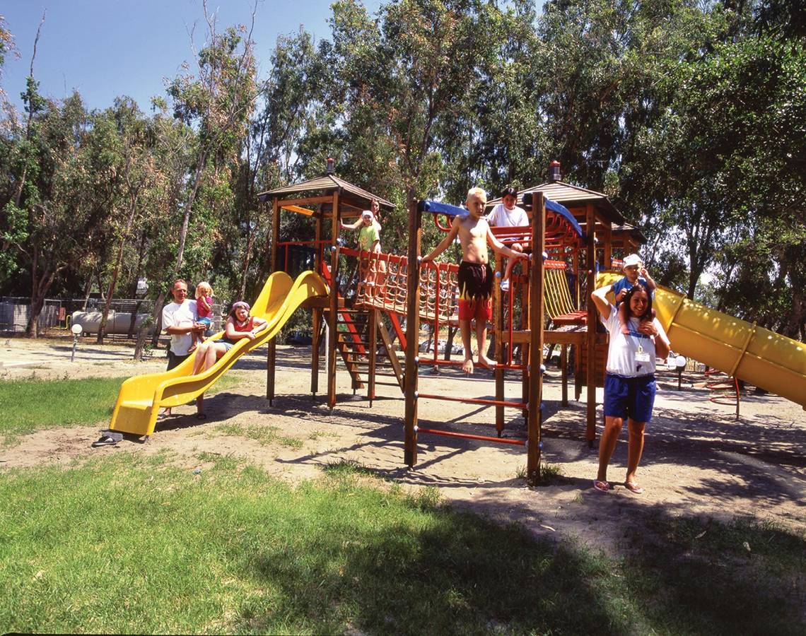 Familie genießt einen Tag auf dem Spielplatz im Freien, mit Rutschen und Klettergerüsten