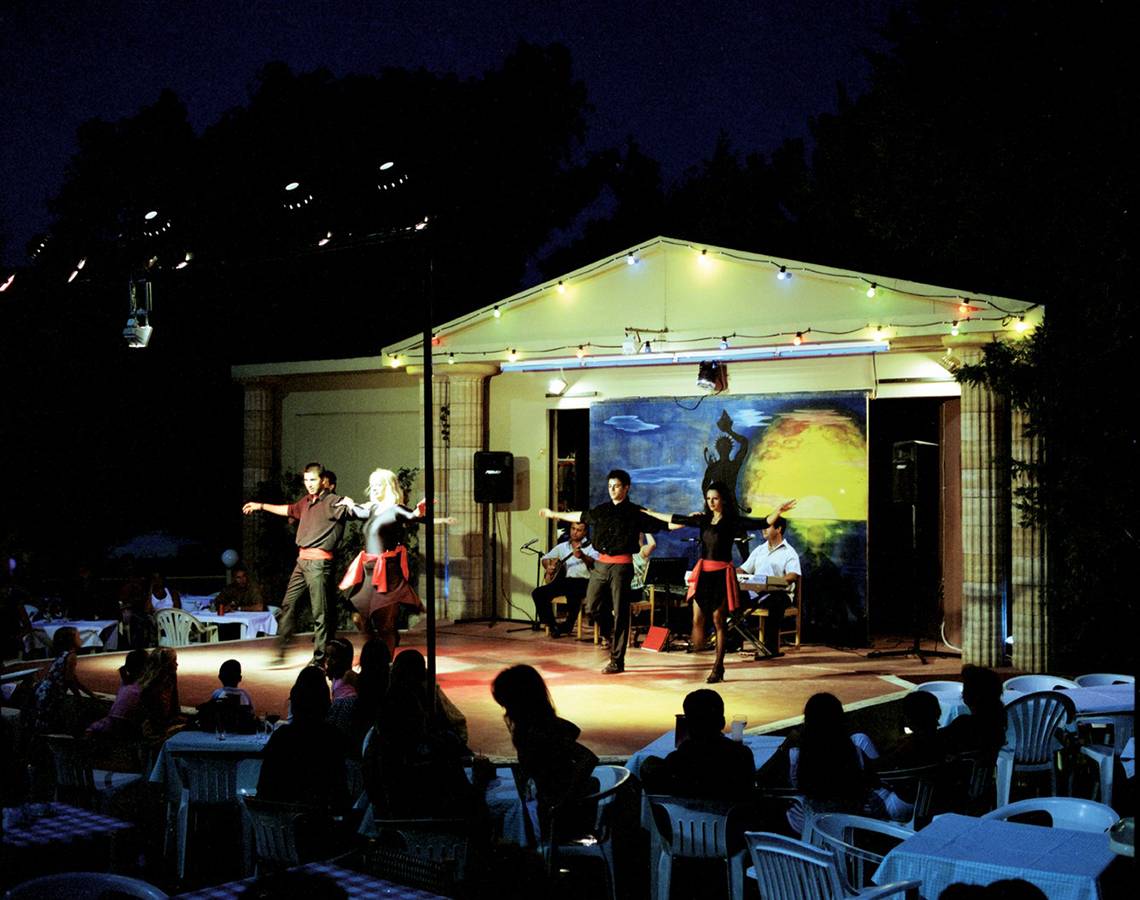 Abendveranstaltung im Hotel Calypso Beach mit Tänzern auf der Bühne und Publikum in weißen Stühlen.