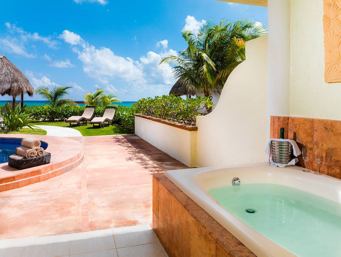 Außenbereich des El Dorado Royale Spa Resorts mit Whirlpool, Lounge-Sesseln und Blick auf den Ozean.