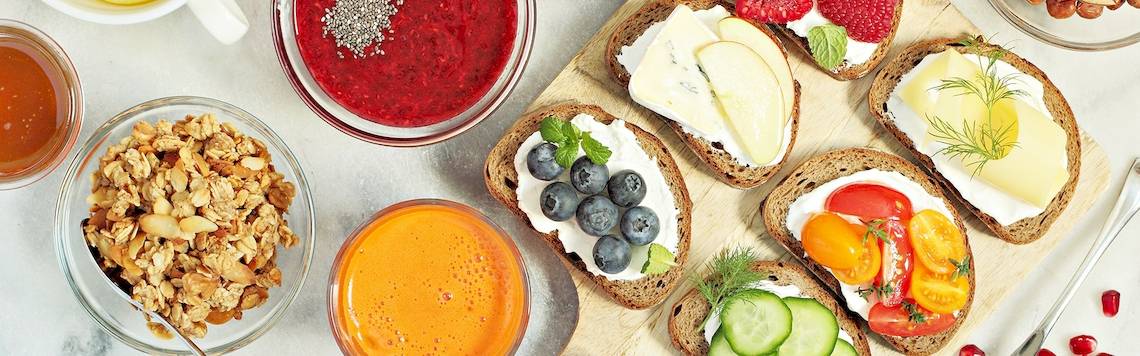 Frühstücksplatte mit Obst, Gemüse und Aufstrich auf einem Holzbrett