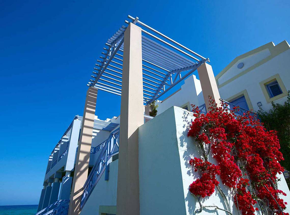 Außenbereich des Serita Beach Hotels mit roter Kletterpflanze und blauer Pergola
