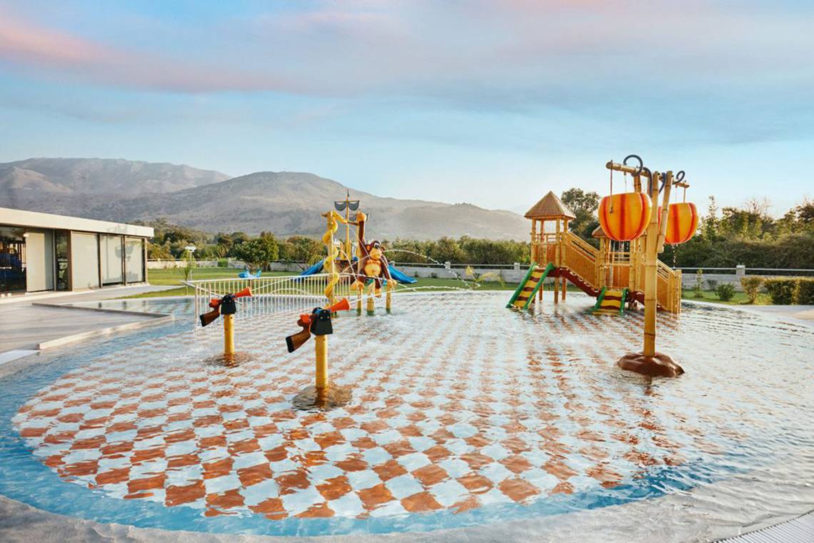 Annas House Spielplatz mit Wasserspielanlage und Bergpanorama im Hintergrund.