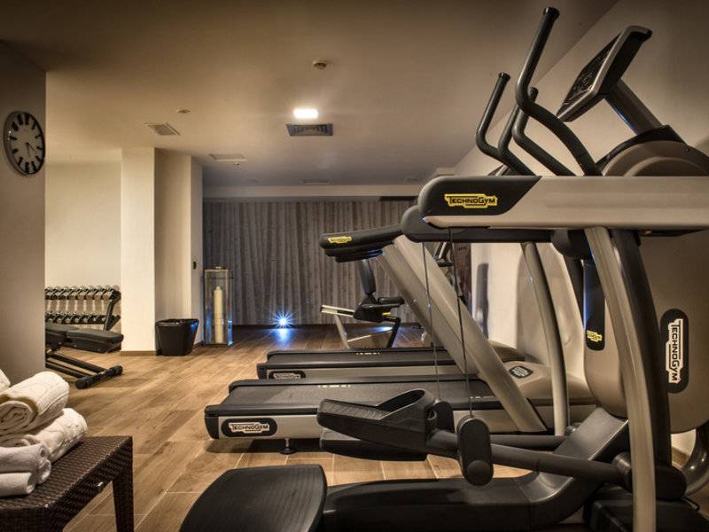 Fitnessraum im Grand Hotel Resort Ma&Ma mit drei Laufbändern und anderen Trainingsgeräten.
