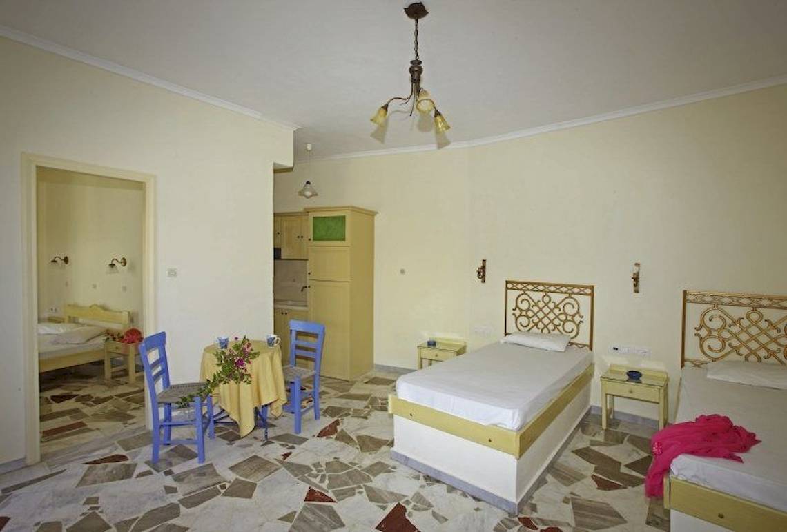 Ein Schlafzimmer im Corissia Beach Hotel mit zwei Betten, gelben Stühlen und einem Tisch.
