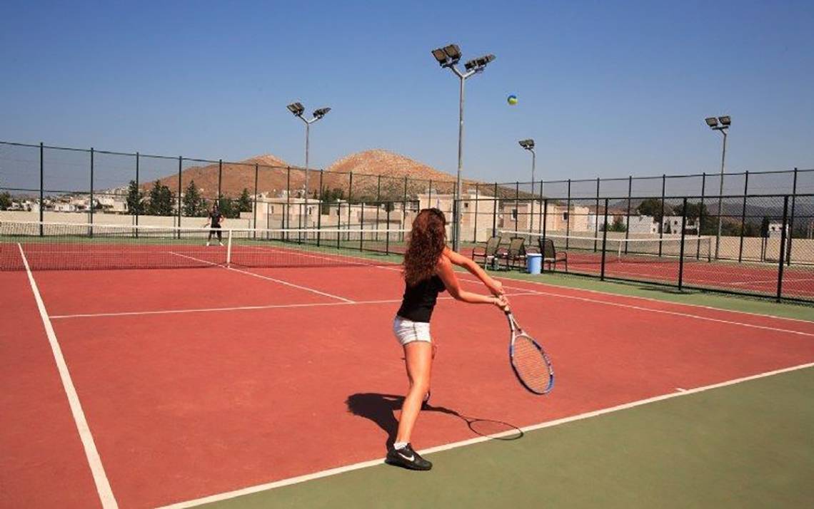 Tennisplatz im La Blanche Resort & Spa mit einer Spielerin, die einen Ball schlägt.