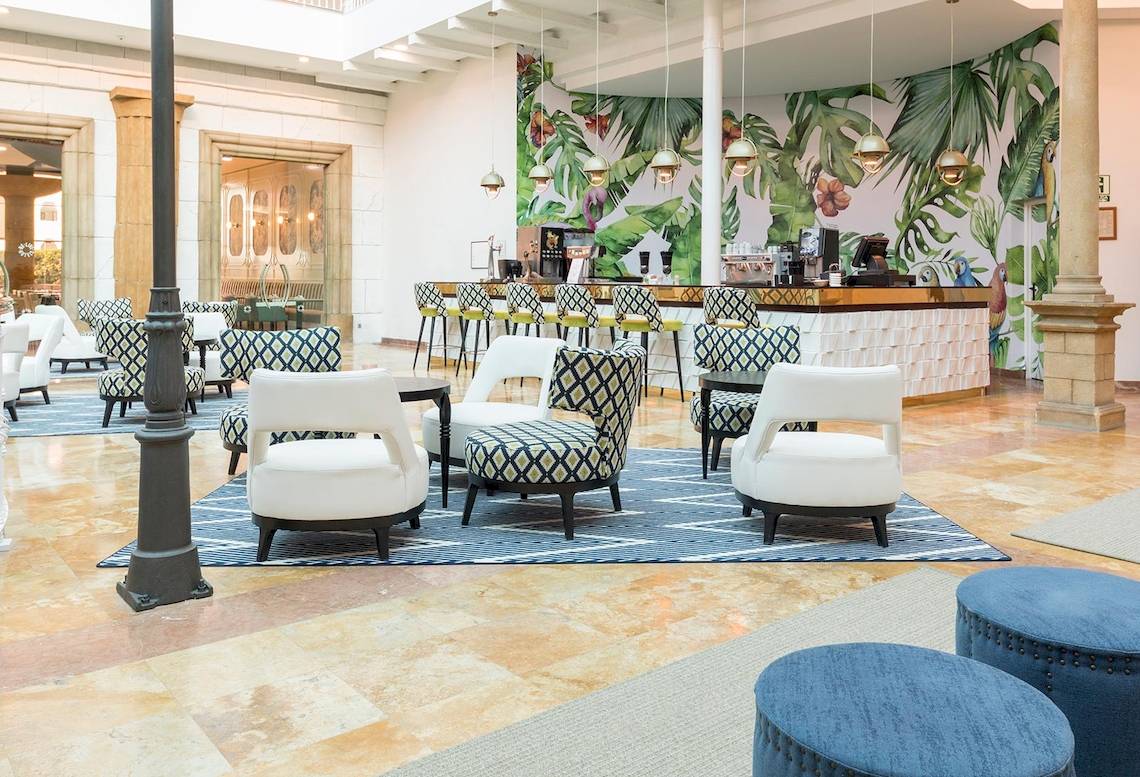 Lobby des Be Live Experience La Nina Hotels mit blauen Teppichen und tropischen Wandmalereien.