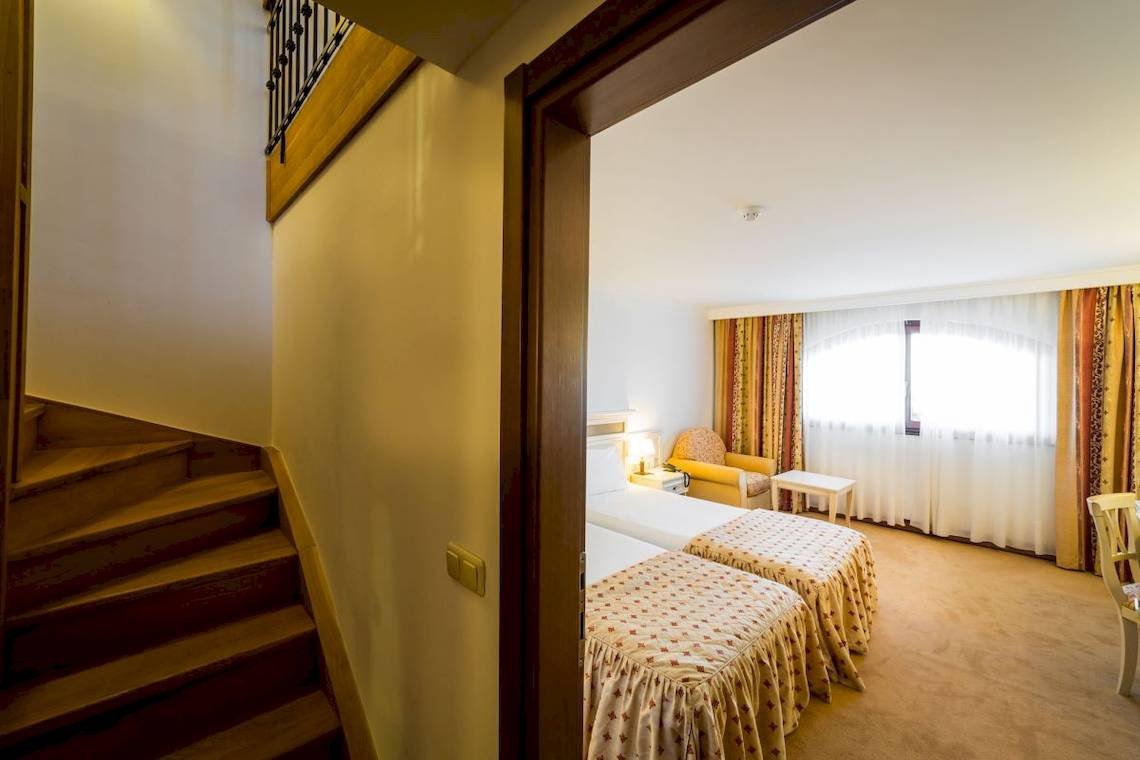 Doppelzimmer im Helena Sands Hotel mit zwei Betten und einem Fenster mit Vorhängen.