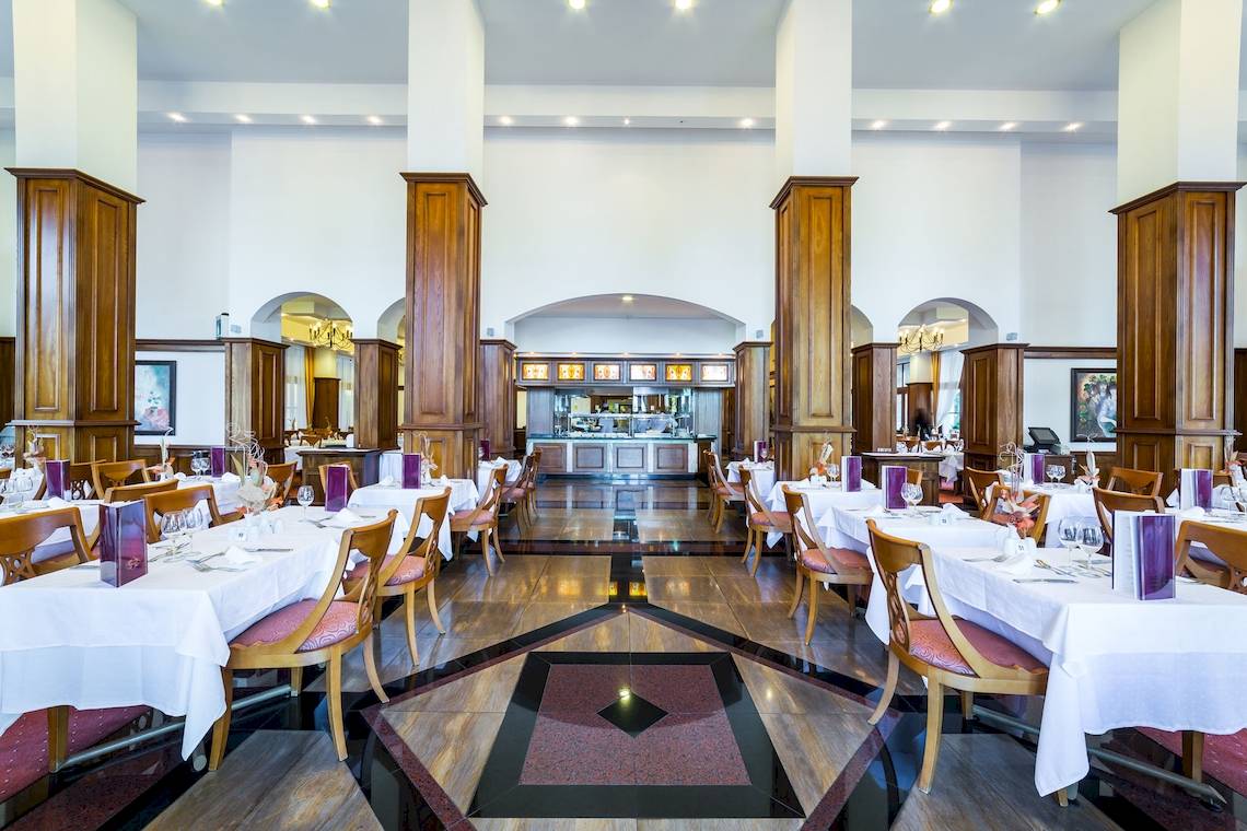 Innenansicht des Restaurants im Helena Sands Hotel mit gedeckten Tischen und Holzsäulen.