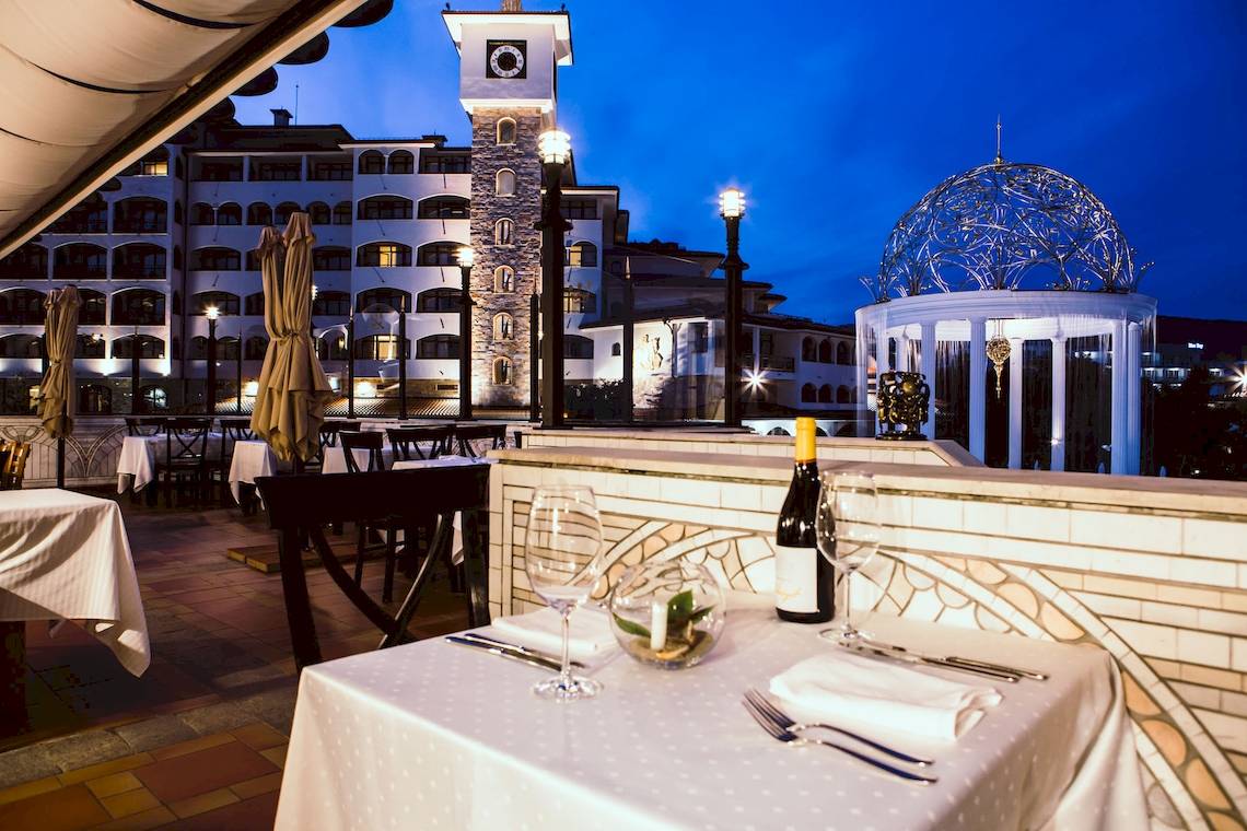 Abendessen auf der Terrasse des Helena Sands Hotels mit Tisch, Wein und Aussicht auf das Gebäude.
