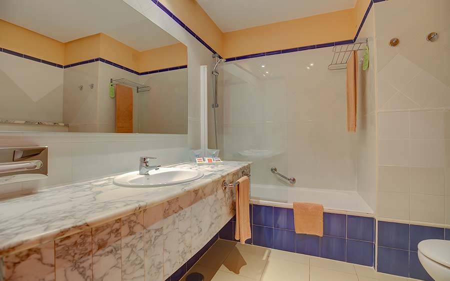 SBH Costa Calma Beach Resort Badezimmer mit Marmor-Waschtisch, Dusche und Badewanne.