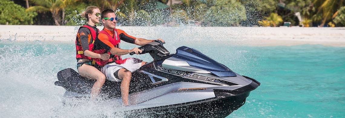 Zwei Personen genießen eine Jetski-Fahrt im Meer vor dem Meeru Island Resort & Spa.
