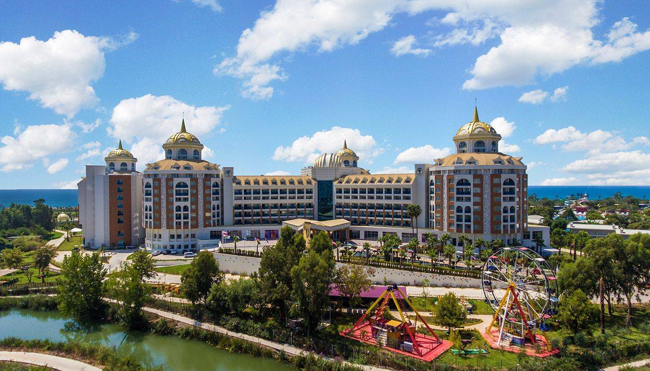 Luftaufnahme des Delphin BE Grand Resort mit Meer und Vergnügungspark im Vordergrund