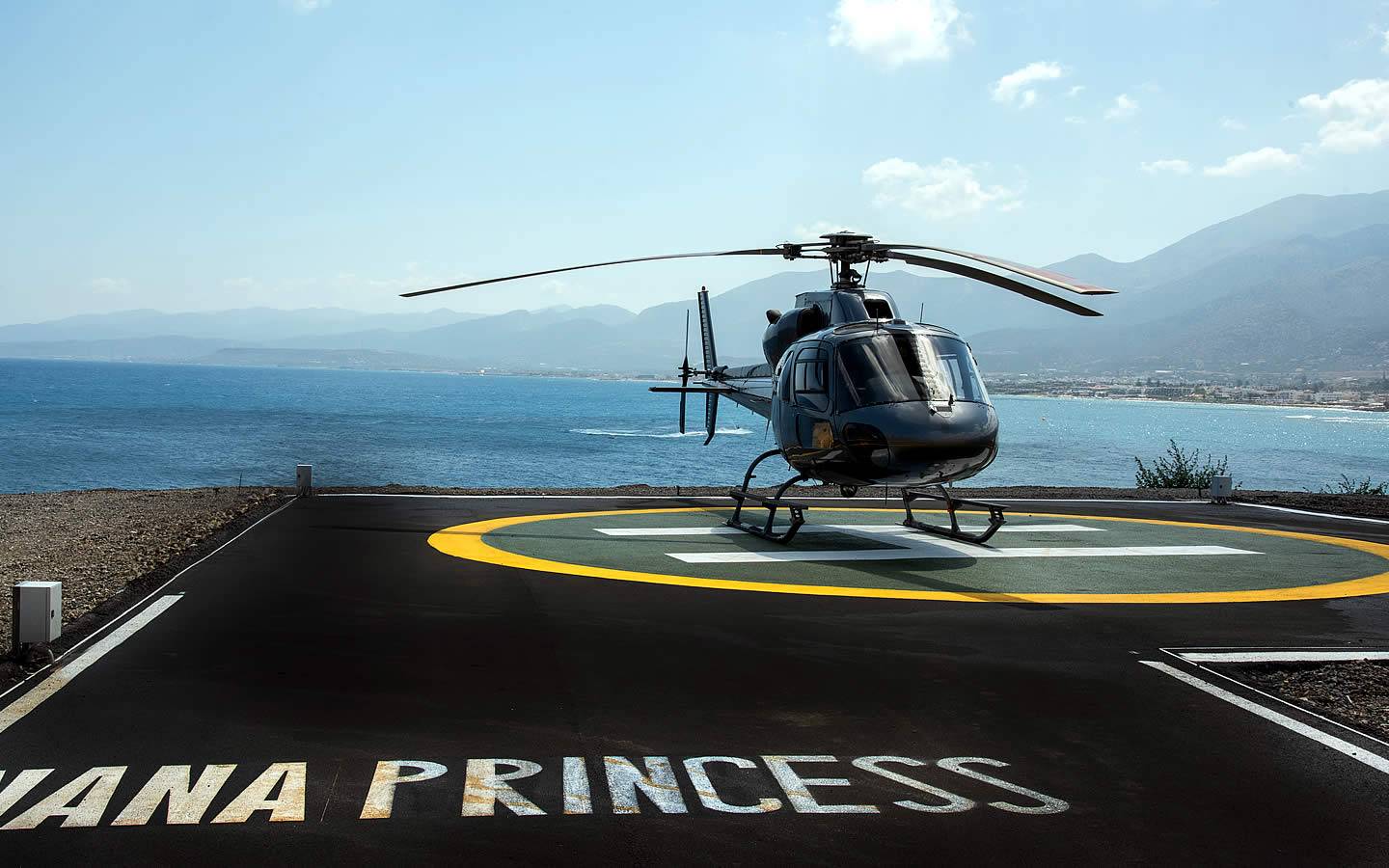Ein schwarzer Hubschrauber der Nana Princess steht auf einem Landeplatz am Strand.