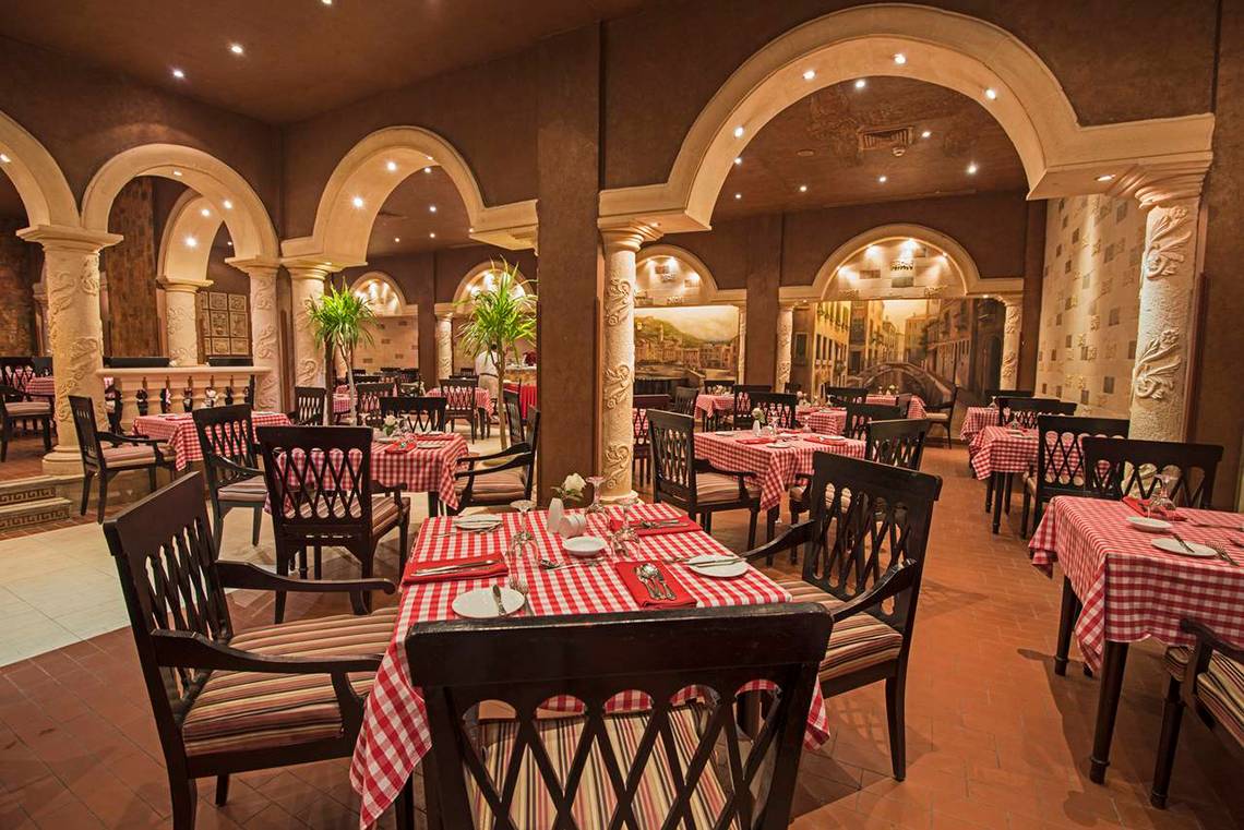 Restaurant im Sunrise Royal Makadi Resort mit roten und weißen Tischdecken.