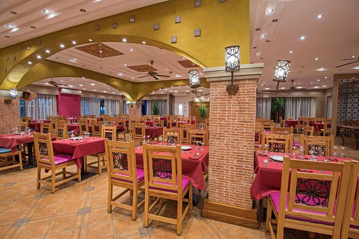 Innenbereich eines Restaurants im Sunrise Royal Makadi Resort mit gedeckten Tischen und Stühlen.