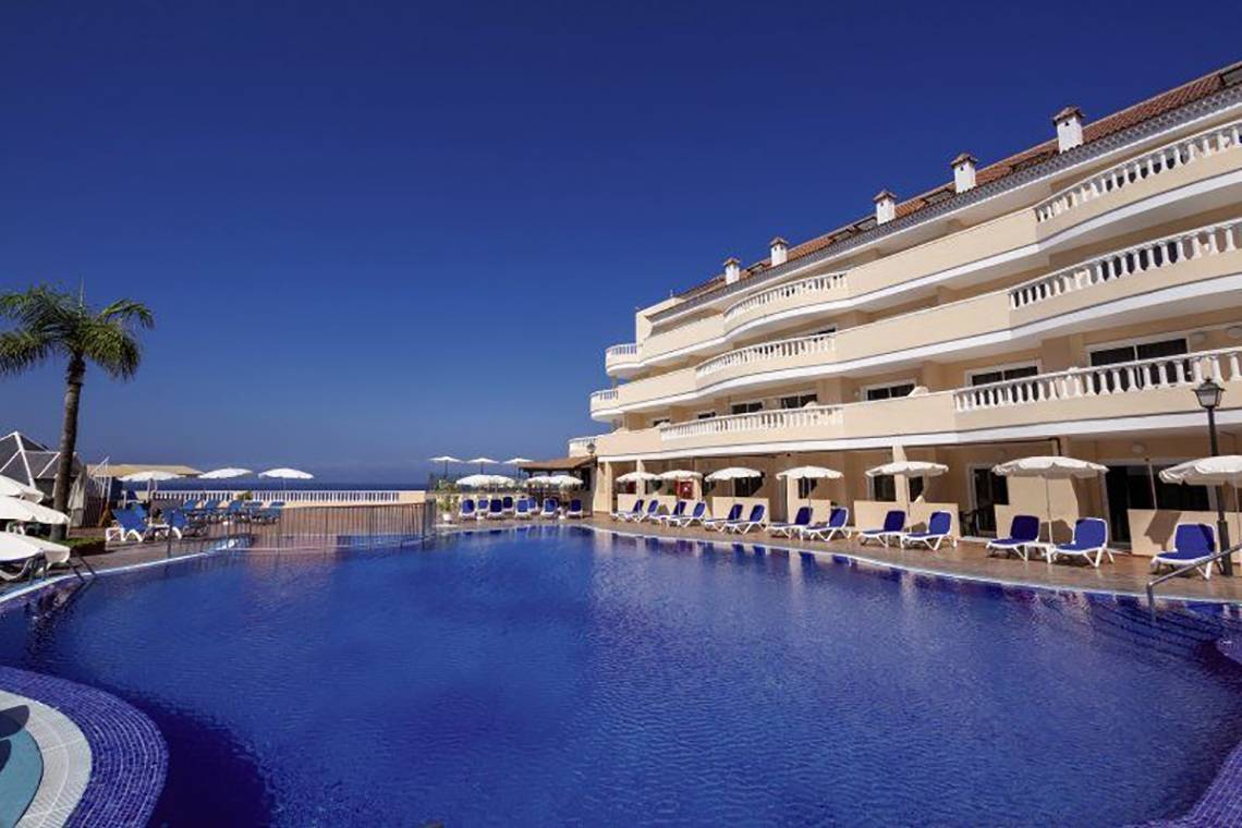 Außenbereich des Bahia Flamingo Hotels mit Swimmingpool, Sonnenliegen und Palme