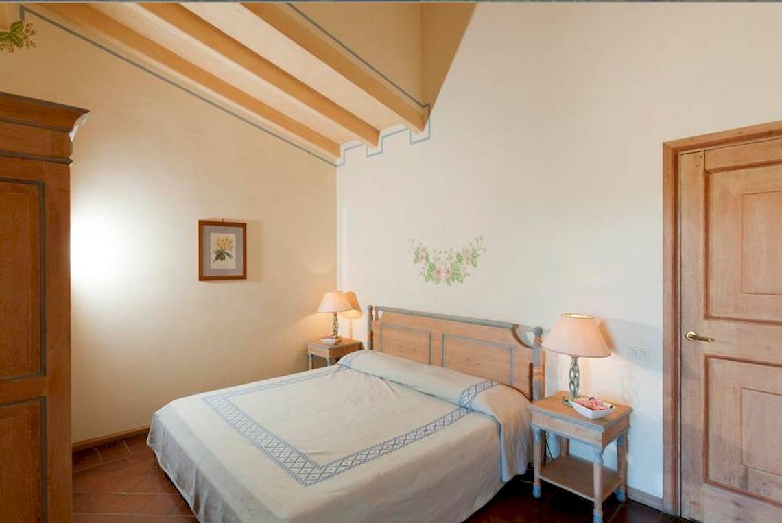Schlafzimmer im Bagaglino I Giardini di Porto Cervo Hotel mit Bett, Nachttischen und Lampen.