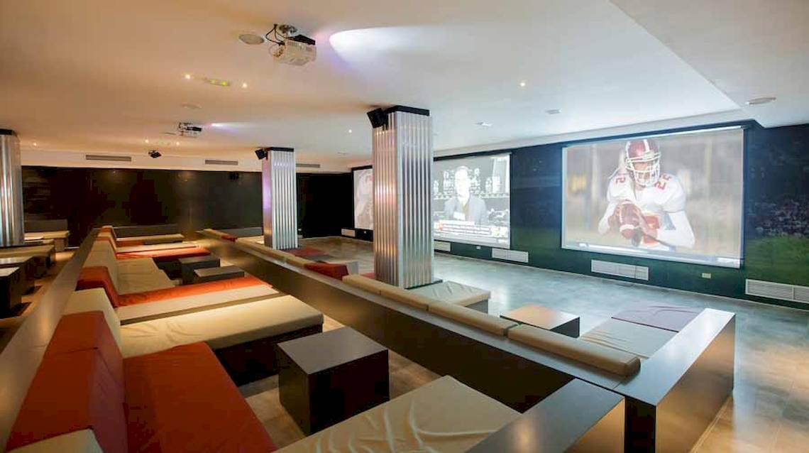 Kinosaal im Majestic Elegance Hotel in Punta Cana mit mehreren Sofas und Bildschirmen.