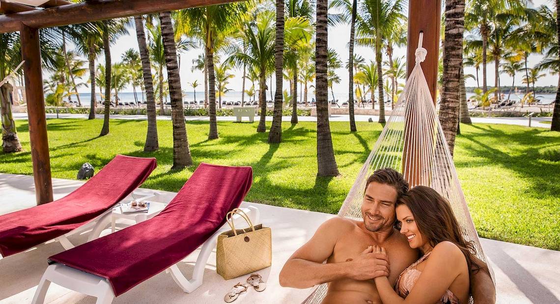 Paar im Hammock im Barcelo Maya Grand Resort neben zwei Lounge-Liegestühlen